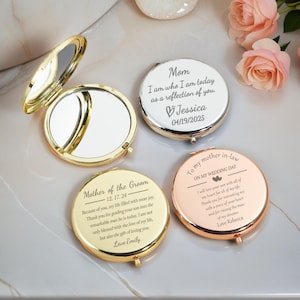 May include: Four personalized compact mirrors in gold, silver, and rose gold. One mirror is open, revealing a reflective surface. The other three mirrors have engraved messages, including names and dates, perfect for wedding gifts.