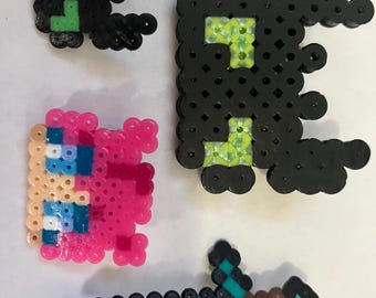 May include: Four pixel art creations: two black figures with green accents, a pink figure with blue accents, and a sword with a teal blade and brown handle. These are likely inspired by a video game.