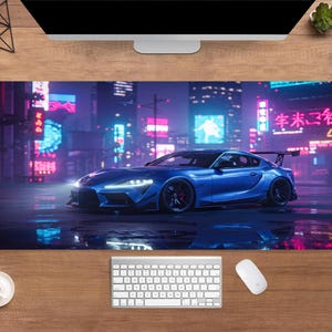 May include: A blue sports car mousepad featuring a futuristic cityscape with neon signs. The car has a spoiler and is parked on a wet surface. The background includes Japanese text and bright lights.