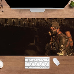 May include: A rectangular desk mat featuring a detailed illustration of a person in a gas mask and military gear. The background depicts a post-apocalyptic scene with a building and vehicles. The color palette is dominated by dark browns and oranges.