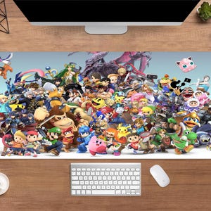 Könnte beinhalten: Eine große, rechteckige Schreibtischunterlage mit einer farbenfrohen Collage von Videospielcharakteren. Das Design zeigt Charaktere aus verschiedenen Spielen vor einem hellblauen Hintergrund. Eine Tastatur und eine Maus sind sichtbar.