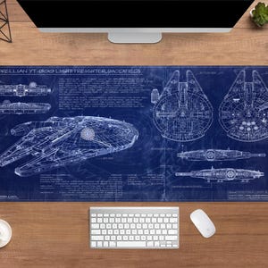 Könnte beinhalten: Blaues Schreibtisch-Pad mit einem Blaupaun-Design des Corellian YT-1300 Light Freighter (Modified). Das Design umfasst detaillierte Schemata und technische Zeichnungen des Raumschiffs. Eine Tastatur, eine Maus und eine Kaffeetasse sind sichtbar.