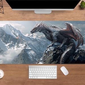 Puede incluir: Alfombrilla de ratón rectangular con una ilustración detallada de un dragón posado en la cima de una montaña rocosa. El dragón es predominantemente gris con acentos de alas rojas, sobre un fondo de montañas nevadas y cielo nublado.