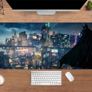 Puede incluir: Alfombrilla de escritorio rectangular con una detallada escena urbana y una figura de Batman recortada contra un cielo nocturno lluvioso. La alfombrilla tiene una combinación de colores oscuros con luces de neón vibrantes.