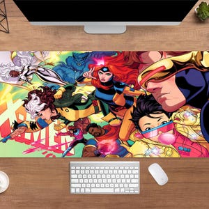 May include: A rectangular desk mat featuring a vibrant comic book illustration of X-Men characters. The design includes characters like Cyclops, Jean Grey, and Rogue, set against a colorful background. A keyboard, mouse, and coffee cup are visible.