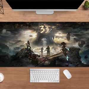 Könnte beinhalten: Rechteckiges Gaming-Mauspad mit Fantasy-Landschaft und der Zahl "33". Das Kunstwerk zeigt eine dramatische Szene mit Figuren, Strukturen und einem dunklen, bewölkten Himmel. Das Pad ist für die Verwendung mit Maus und Tastatur konzipiert.