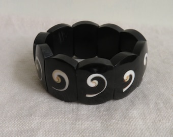 May include: Black elastic bracelet with white and gold swirl designs.