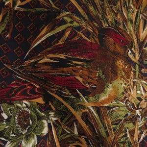 Puede incluir: Una tela con un dise&ntilde;o detallado de p&aacute;jaro y follaje. El p&aacute;jaro presenta tonos de marr&oacute;n, rojo y verde, sobre un fondo de plantas estilizadas y un patr&oacute;n de diamantes azul oscuro. La est&eacute;tica general recuerda a los textiles vintage.