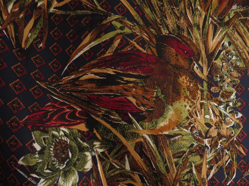 Puede incluir: Una tela con un dise&ntilde;o detallado de p&aacute;jaro y follaje. El p&aacute;jaro presenta tonos de marr&oacute;n, rojo y verde, sobre un fondo de plantas estilizadas y un patr&oacute;n de diamantes azul oscuro. La est&eacute;tica general recuerda a los textiles vintage.