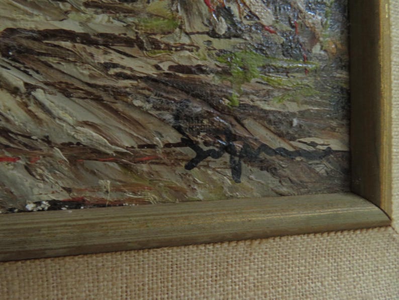 Puede incluir: Pintura al &oacute;leo de estilo impresionista texturizado. La obra de arte presenta un paisaje con tonos marrones, beige y verdes. La pintura est&aacute; enmarcada en un marco de madera marr&oacute;n claro y descansa sobre una tela beige.