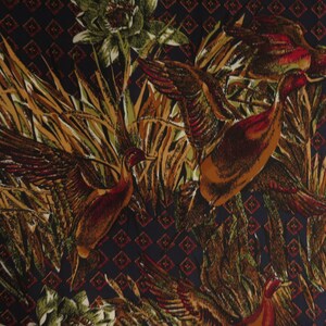 Puede incluir: Una tela con un patr&oacute;n repetido de patos en vuelo entre juncos y follaje. Los patos est&aacute;n representados en tonos marrones, naranjas y rojos, con las alas extendidas. El fondo es azul oscuro con un patr&oacute;n de diamantes.