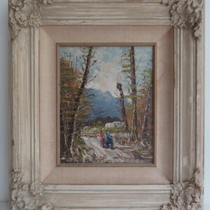 Puede incluir: Pintura al &oacute;leo de un paisaje con un camino, &aacute;rboles y monta&ntilde;as. La obra de arte est&aacute; enmarcada en un marco desgastado, ornamentado, blanquecino. La pintura representa dos figuras caminando por un sendero.