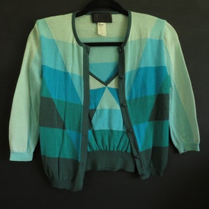 May include: A blue and green geometric patterned cardigan with a matching top. The cardigan has a button closure and long sleeves.