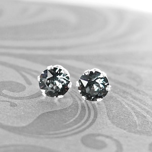 May include: A pair of silver stud earrings with dark gray round gemstones.
