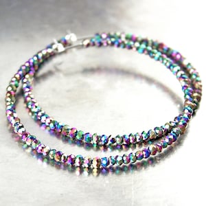 May include: A pair of iridescent hoop earrings made with small faceted beads. The earrings are silver-toned and have a double hoop design.