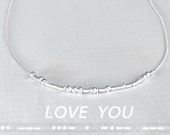 May include: A silver necklace with a delicate chain and small silver beads spelling out "LOVE YOU".