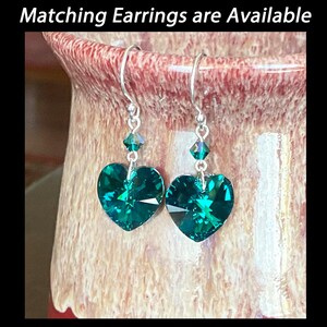 May include: A pair of silver heart-shaped earrings with emerald green crystal accents.