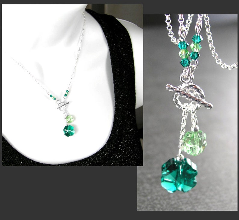Puede incluir: Un collar de plata con cierre de palanca y dos colgantes de cristal verde. Los colgantes tienen forma de tr&eacute;bol de cuatro hojas. El collar est&aacute; en un maniqu&iacute; blanco que lleva una camiseta sin mangas negra.