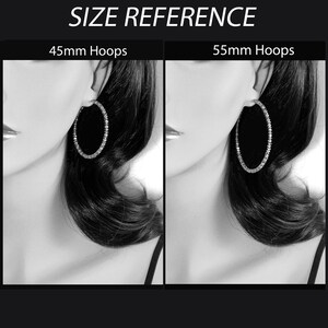 May include: A side-by-side comparison of two sizes of hoop earrings. The earrings are silver and have a row of clear rhinestones around the hoop. The left earring is 45mm and the right earring is 55mm.