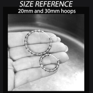 May include: Two pairs of silver hoop earrings with crystal beads. The larger pair is 30mm in diameter and the smaller pair is 20mm in diameter.