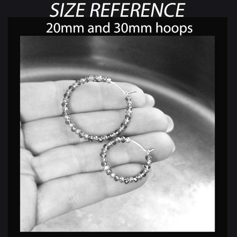 May include: Two pairs of silver hoop earrings with crystal beads. The larger pair is 30mm in diameter and the smaller pair is 20mm in diameter.