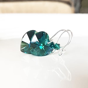 May include: Teal heart-shaped crystal earrings with silver hooks.