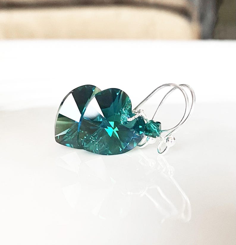 May include: Teal heart-shaped crystal earrings with silver hooks.