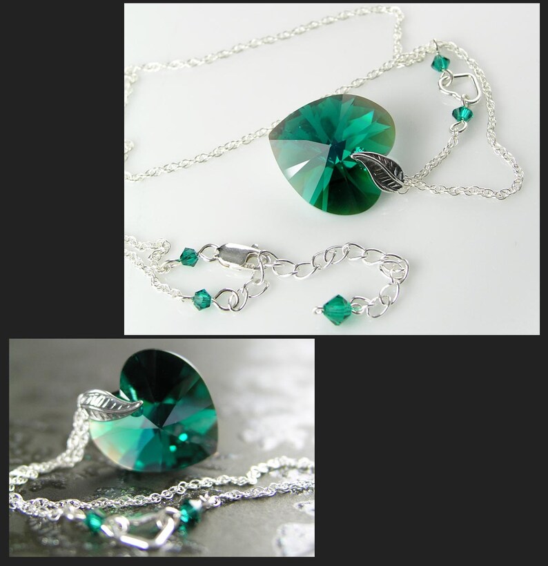 May include: A silver chain necklace with a large emerald green heart-shaped crystal pendant. The pendant has a small silver leaf charm attached to it.
