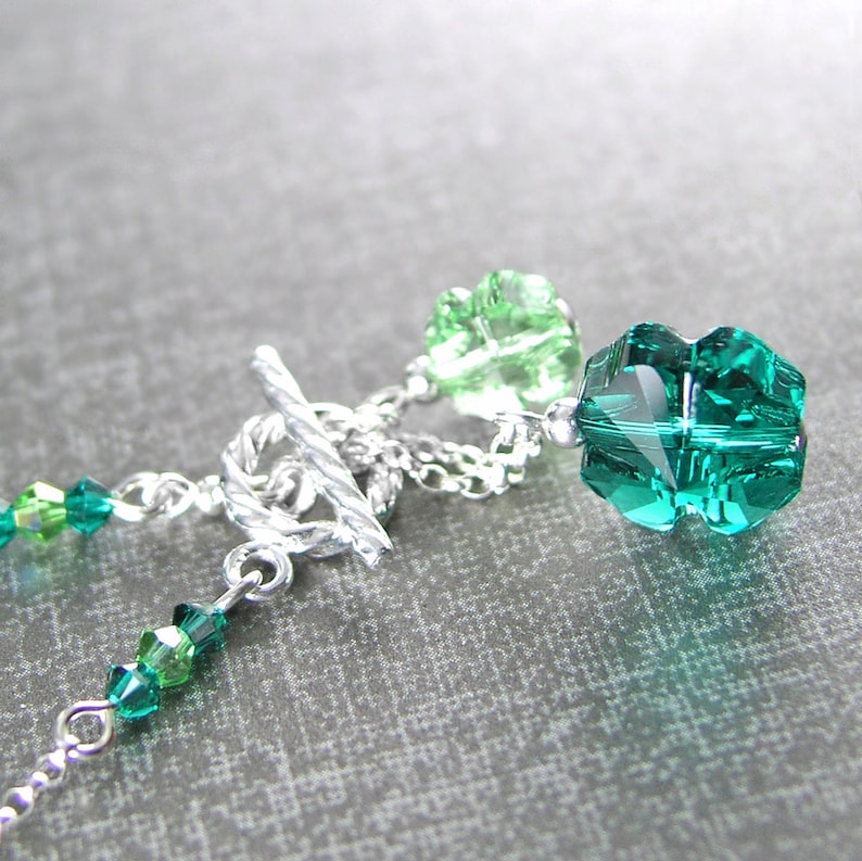 Puede incluir: Un brazalete de cadena de plata con un cierre de palanca y cuentas de cristal verde. Las cuentas son facetadas y tienen un degradado de tonos verdes.