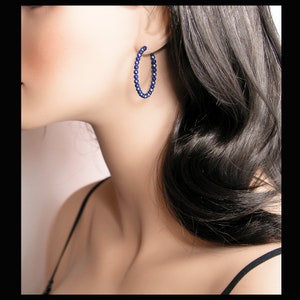 May include: A pair of hoop earrings made of small, dark blue beads.