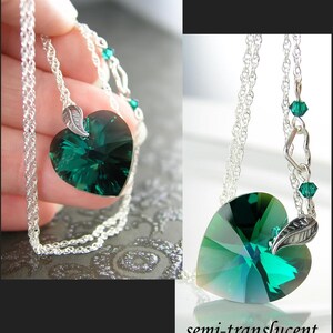 May include: A silver chain necklace with a green heart-shaped crystal pendant and a silver leaf charm. The crystal is semi-translucent and has a faceted design.