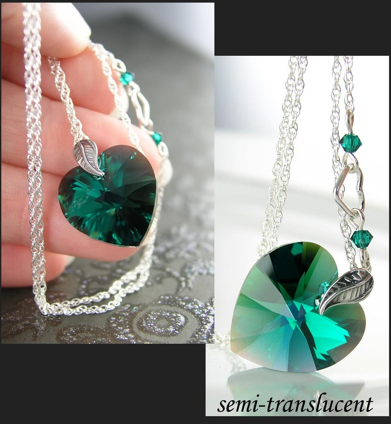 May include: A silver chain necklace with a green heart-shaped crystal pendant and a silver leaf charm. The crystal is semi-translucent and has a faceted design.