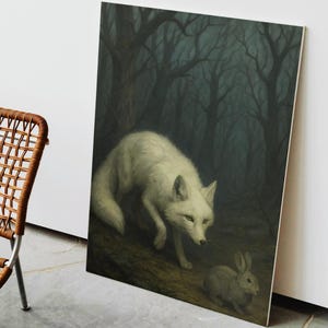 May include: A framed art print depicts a white fox and a gray rabbit in a dark forest. The fox is the focal point, with its white fur contrasting against the dark background. The artwork evokes a sense of mystery and nature.