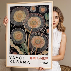 May include: A framed art print featuring a black background with large, circular, dandelion-like floral patterns in shades of orange, yellow, and white. The text at the bottom reads YAYOI KUSAMA, the Japanese characters for infinite world, and TOKYO.