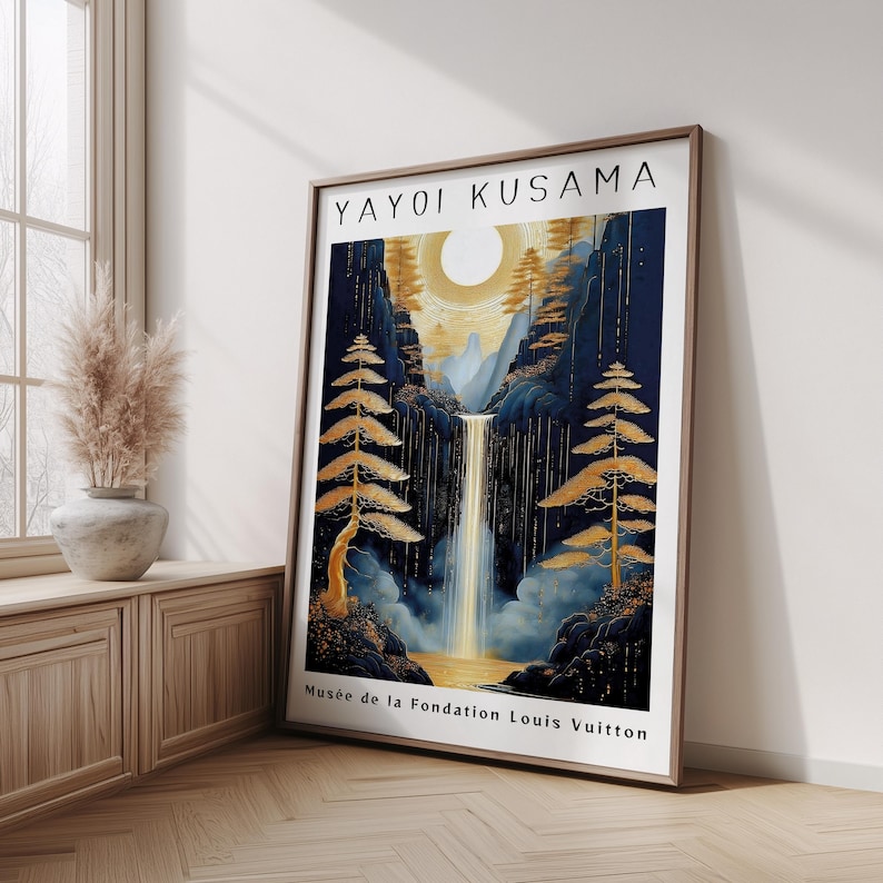 K&ouml;nnte beinhalten: Ein gerahmter Kunstdruck mit einer Wasserfallszene mit goldener Sonne und B&auml;umen. Das Kunstwerk ist mit "Yayoi Kusama" signiert und tr&auml;gt den Text "Mus&eacute;e de la Fondation Louis Vuitton". Der Druck steht auf einem Holzboden.