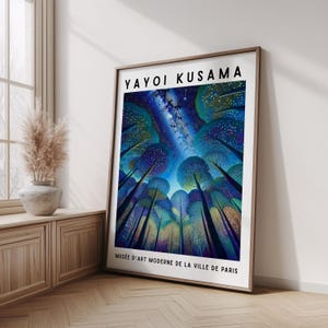 May include: A framed art print displaying a colourful illustration of trees under a starry night sky. The artwork is signed "YAYOI KUSAMA" and includes the text "MUSÉE D'ART MODERNE DE LA VILLE DE PARIS". The print is displayed on a wooden floor.