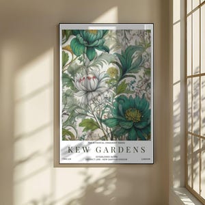 K&ouml;nnte beinhalten: Ein gerahmter Kunstdruck mit einem detaillierten floralen Design in Gr&uuml;n-, Wei&szlig;- und Gelbt&ouml;nen. Der Druck enth&auml;lt den Text &bdquo;KEW GARDENS&ldquo; und weiteren Text. Das Kunstwerk wird an einer Wand in der N&auml;he eines Fensters gezeigt.
