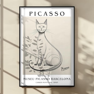 May include: A framed art print featuring a stylized black and white illustration of a cat, with the name "Picasso" at the top. The print includes the text "The Cat" and "Museu Picasso Barcelona, Carrer Montcada - Spain."