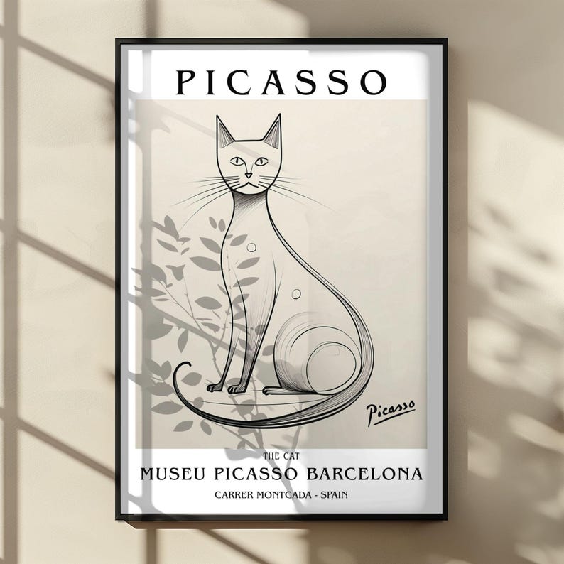 May include: A framed art print featuring a stylized black and white illustration of a cat, with the name "Picasso" at the top. The print includes the text "The Cat" and "Museu Picasso Barcelona, Carrer Montcada - Spain."