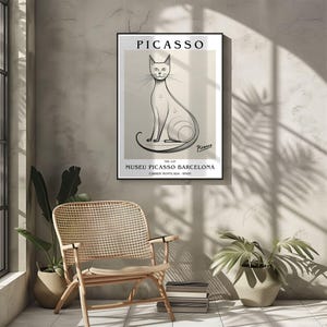 May include: A framed art print featuring a minimalist illustration of a cat by Picasso. The artwork is in black and white, with the name "PICASSO" at the top and "MUSEU PICASSO BARCELONA" at the bottom. The print is displayed on a neutral-toned wall.