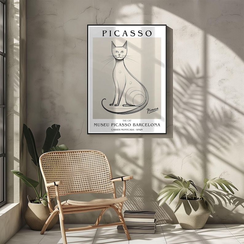 May include: A framed art print featuring a minimalist illustration of a cat by Picasso. The artwork is in black and white, with the name "PICASSO" at the top and "MUSEU PICASSO BARCELONA" at the bottom. The print is displayed on a neutral-toned wall.