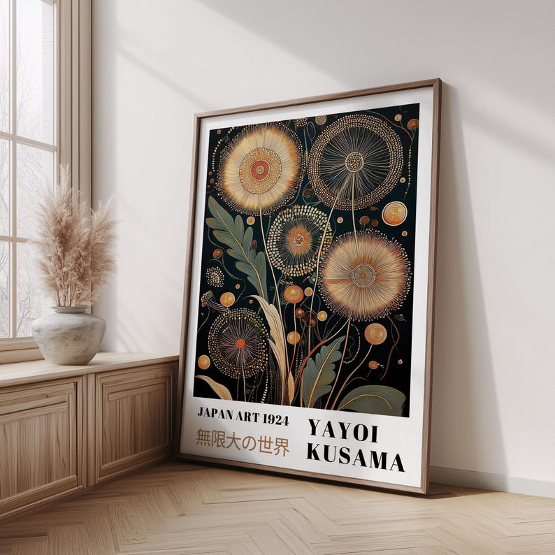 May include: Framed art print featuring a floral design with gold and orange accents on a dark background. The print includes text that reads "JAPAN ART 1924" and "YAYOI KUSAMA". The artwork is displayed in a room with a window and wooden furniture.