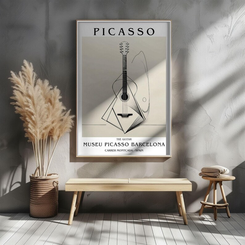 Puede incluir: Un p&oacute;ster enmarcado con una ilustraci&oacute;n en blanco y negro de una guitarra, con el nombre "PICASSO" en la parte superior. Tambi&eacute;n incluye el texto "MUSEU PICASSO BARCELONA". La obra de arte se exhibe en una habitaci&oacute;n con un banco y plantas decorativas.
