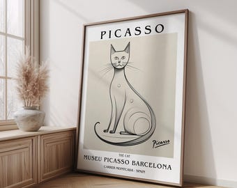 May include: A framed art print featuring a stylized black and white illustration of a cat, with the name "Picasso" at the top. The print includes text for the Museu Picasso Barcelona.