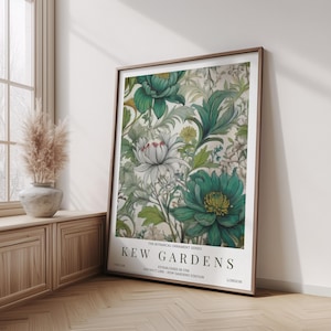 K&ouml;nnte beinhalten: Ein gerahmter Kunstdruck mit einem botanischen Design aus gr&uuml;nen und wei&szlig;en Blumen und Bl&auml;ttern. Der Druck tr&auml;gt die Aufschrift "KEW GARDENS" und "LONDON". Das Kunstwerk wird in einem Raum mit Holzboden und Fenster ausgestellt.