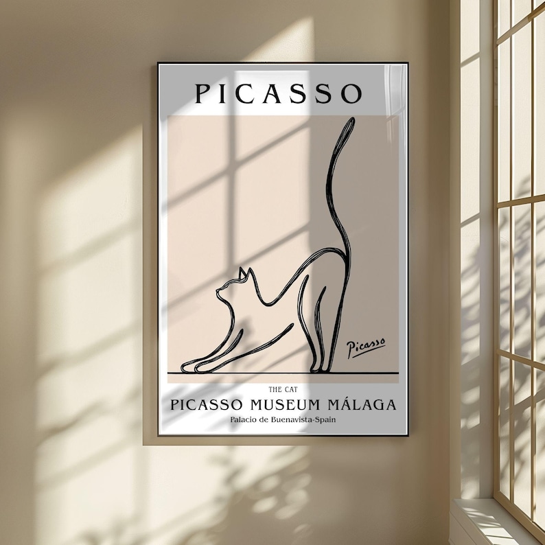 Puede incluir: Un cuadro enmarcado con un dibujo lineal minimalista en negro de un gato estir&aacute;ndose sobre un fondo beige. El cuadro incluye el nombre "PICASSO" en la parte superior y "PICASSO MUSEUM M&Aacute;LAGA" en la inferior, con la firma del artista.