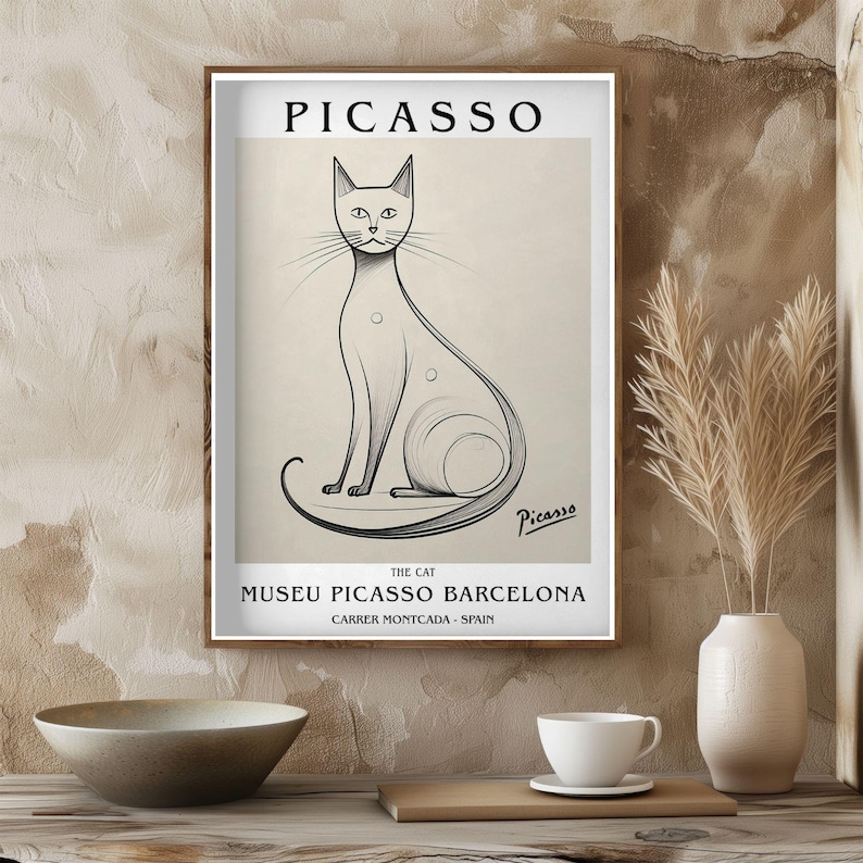 May include: A framed art print featuring a Picasso illustration of a cat. The black and white drawing depicts a seated cat with a long tail. The print includes the name "Picasso" at the top and the text "Museu Picasso Barcelona" at the bottom.