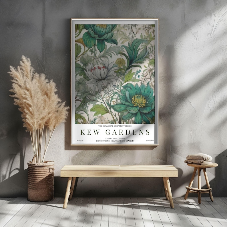 K&ouml;nnte beinhalten: Gerahmter Kunstdruck mit floralem Design in Gr&uuml;n-, Wei&szlig;- und Graut&ouml;nen. Der Druck tr&auml;gt die Aufschrift "Kew Gardens" und wird an einer grauen Wand gezeigt. Eine Holzbank und ein Hocker befinden sich vor der Wand.