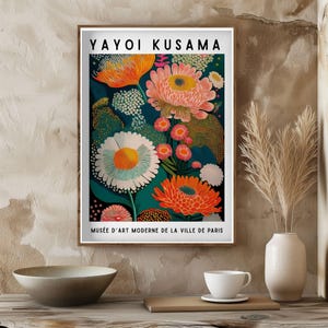 Pode incluir: Uma impress&atilde;o art&iacute;stica emoldurada com um design floral vibrante com grandes flores estilizadas em tons de laranja, rosa e branco sobre um fundo azul escuro. A impress&atilde;o inclui o texto "YAYOI KUSAMA" e "MUS&Eacute;E D'ART MODERNE DE LA VILLE DE PARIS".