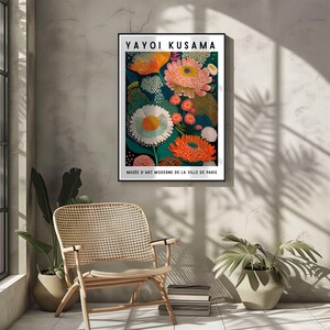 Pode incluir: Uma impress&atilde;o art&iacute;stica emoldurada com um design floral. A obra apresenta grandes flores coloridas em tons de laranja, rosa e branco sobre um fundo azul-petr&oacute;leo escuro. A impress&atilde;o inclui o texto "YAYOI KUSAMA" e "MUS&Eacute;E D'ART MODERNE DE LA VILLE DE PARIS".
